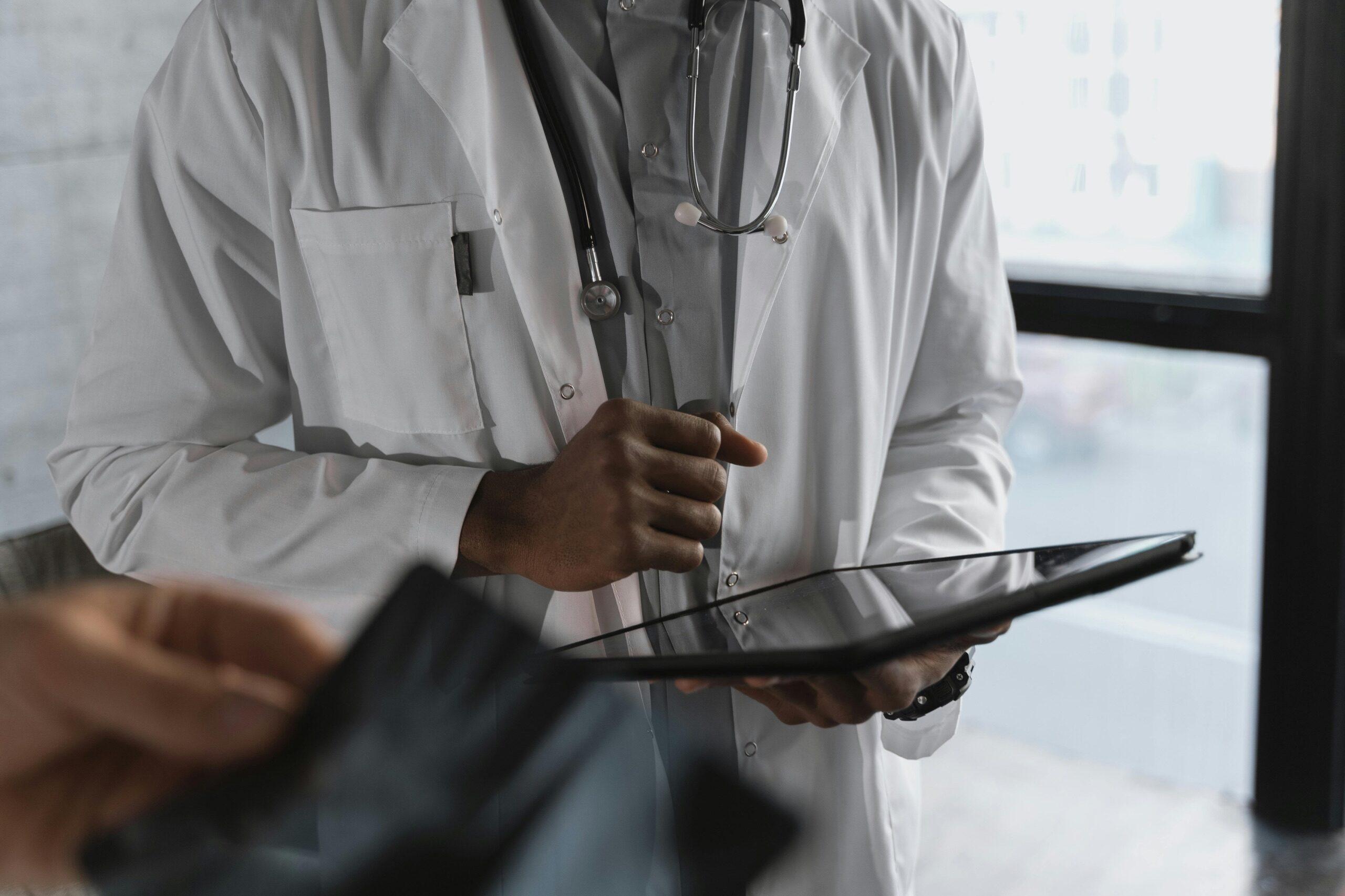 Doctor with stethoscope reviewing patient information on a tablet