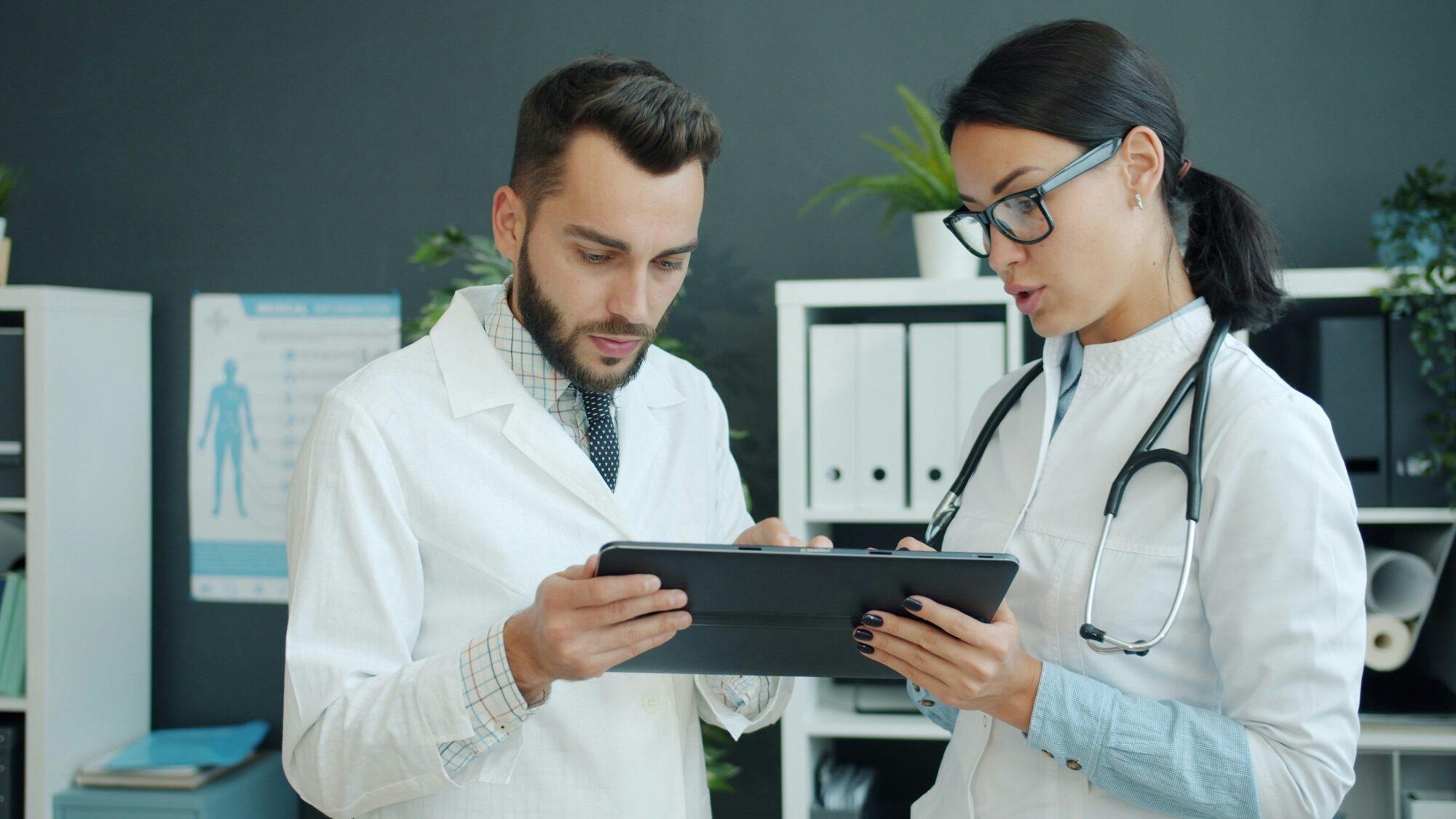 Two healthcare professionals collaborating over a tablet