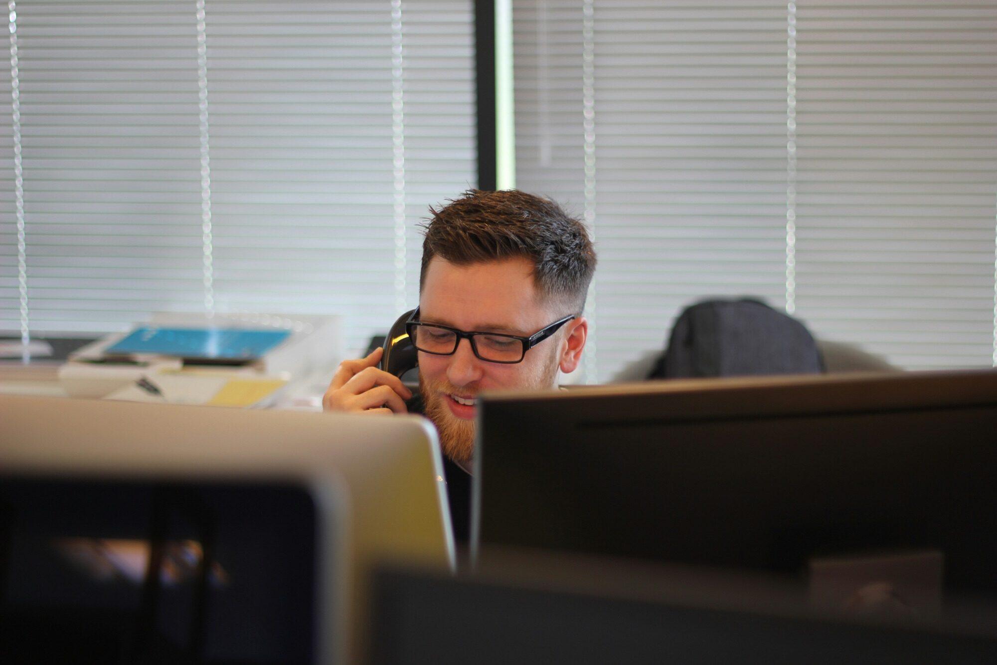 Helpdesk technician on the phone behind monitors